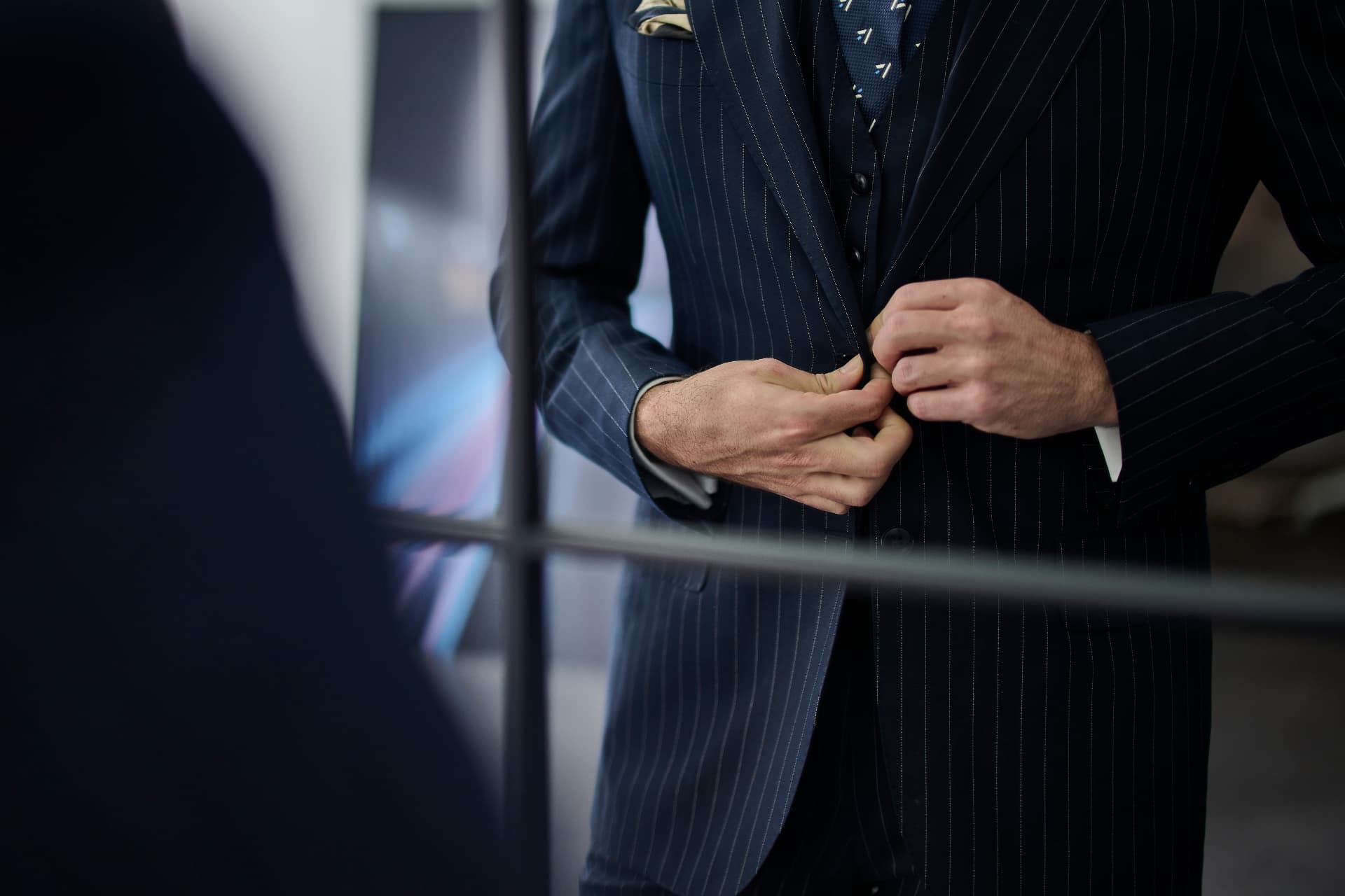 Client buttoning a navy pinstripe John Tailor suit