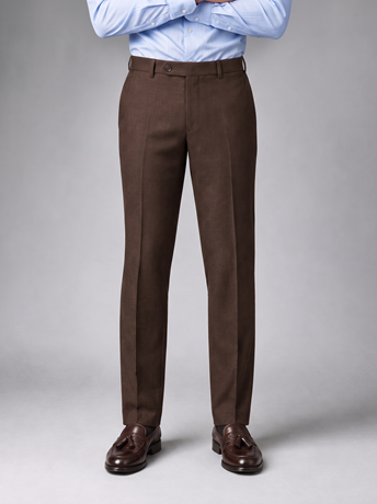 Brown tailored trousers worn with a light blue shirt and dark brown tassel loafers
